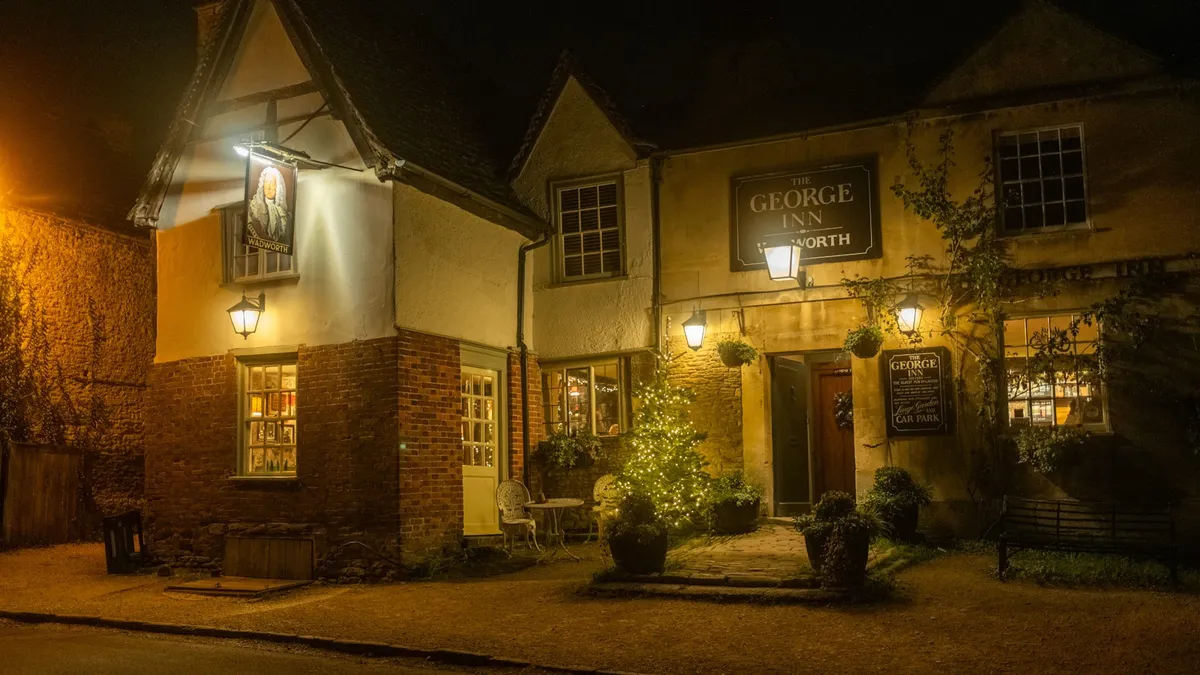 the exterior of a cosy country pub or small holiday let in the evening, warm and inviting